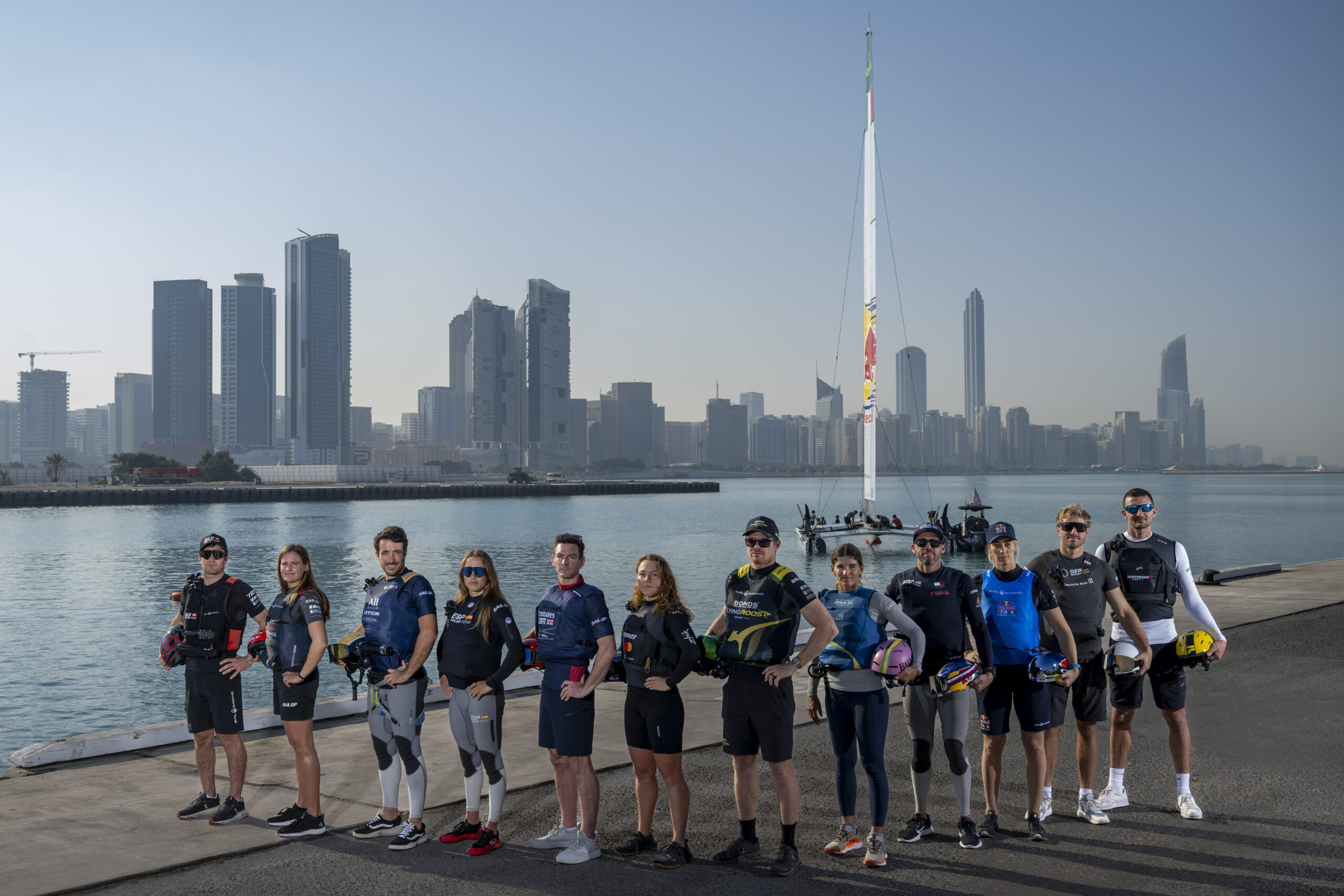 (L-r) Sebastien Schneiter, driver of Switzerland SailGP Team, Kahena Kunze, reserve of ROCKWOOL Denmark SailGP Team on loan from Mubadala Brazil SailGP Team, Quentin Delapierre, driver of Les Bleus SailGP Team, Nicole van der Velden, strategist of Los Gallos SailGP Team, Dylan Fletcher, driver of Emirates Great Britain SailGP Team, Liv Mackay, strategist of Black Foils SailGP Team, Tom Slingsby, driver of BONDS Flying Roos SailGP Team, Martine Grael, driver of Mubadala Brazil SailGP Team, Taylor Canfield, driver of United States SailGP Team, Jana Germani, strategist of Red Bull Italy SailGP Team, Erik Kosegarten Heil, driver of Germany SailGP Team presented by Deutsche Bank, and Giles Scott, driver of NORTHSTAR SailGP Team, stand together in front of the Red Bull Italy SailGP Team F50 catamaran overlooking the Abu Dhabi skyline ahead of the Mubadala Abu Dhabi Sail Grand Prix 2025 Season Grand Final presented by Abu Dhabi Sports Council held in Abu Dhabi, United Arab Emirates, Friday 28 November 2025. Rolex SailGP Championship Event 12 2025 Season. Photo: Ricardo Pinto for SailGP. Handout image supplied by SailGP