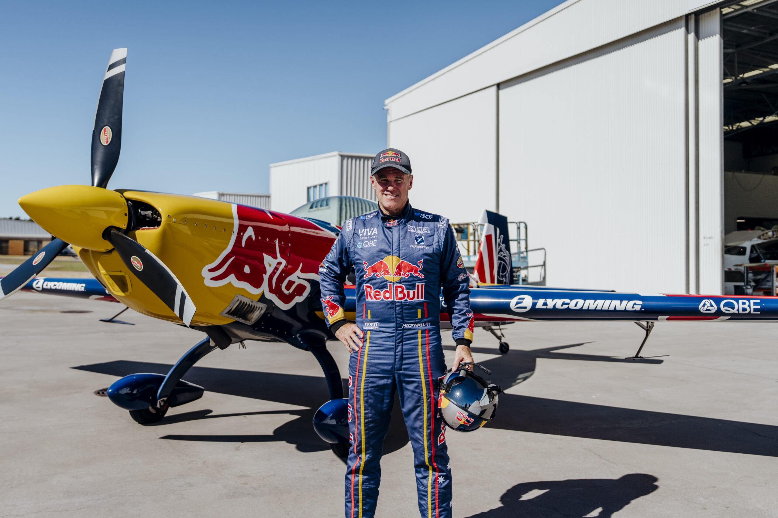 Hero Shot - Matt Hall in Red Bull Racing suit in front of Red Bull Aircraft